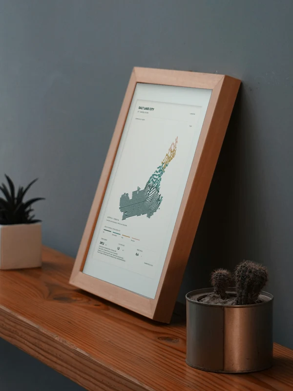 The Salt Lake City artwork digitally placed in a frame on a shelf beside plants. Framing and proportions are illustrative.